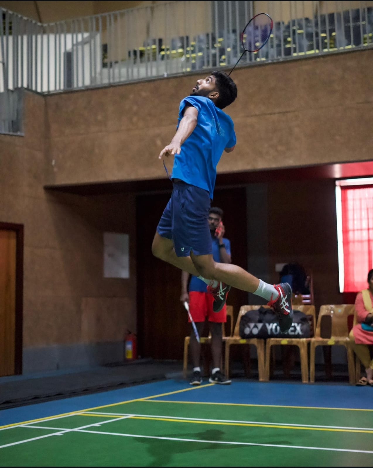 Anirudh jumping to play a badminton shot